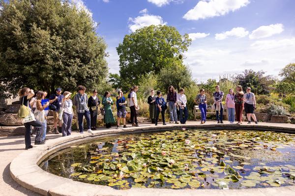 Students stand around a pond at the Oxford botanical gardens