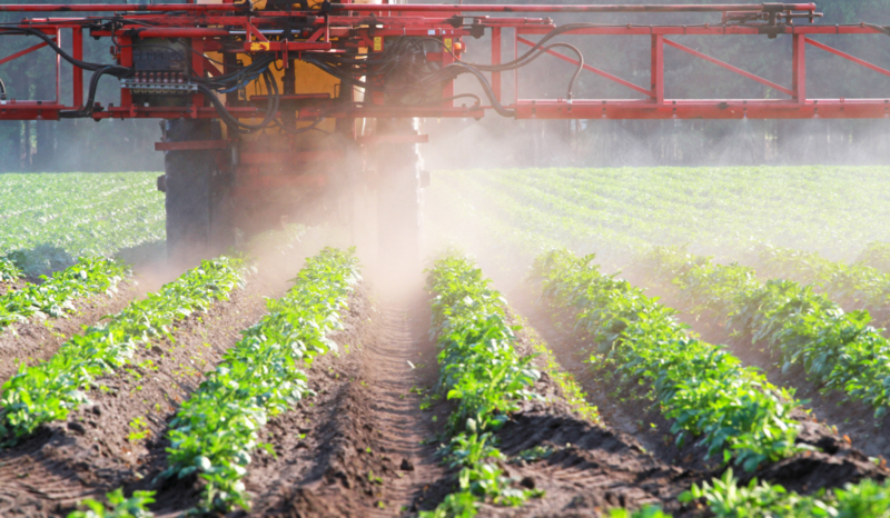 Farm machinery applying herbicides to crops enmasse