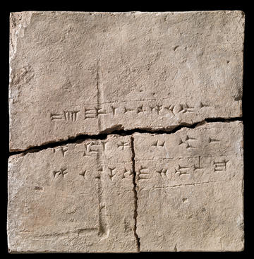 A clay tablet with wedge shaped marks (cuneiform script). The tablet is cracked horizontally and vertically into three pieces.