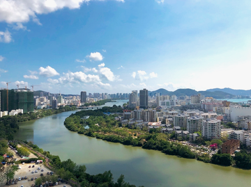 A city next to a river, with greenery beside it. It is an example of urban development with ecological compensation in Sanya, Hanan Island, China