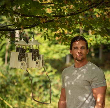 Feeders sam hobson Dr Josh Firth standing in dappled light next to two smart bird feeders