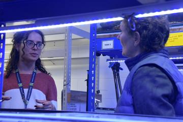 A student talks to the VC in the blue light of the fish labs