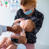 Infant receiving vaccination, held by their parent